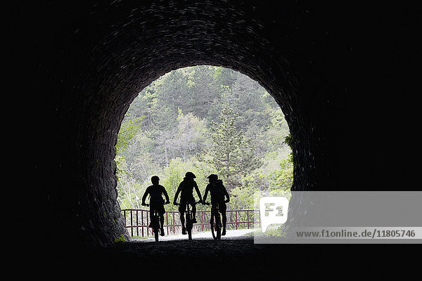Silhouettierte Radfahrer bei der Einfahrt in den Tunnel