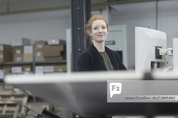 Lächelnder Druckereiarbeiter bei der Arbeit an einer Druckmaschine