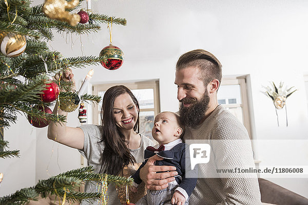 Eltern mit einem kleinen Jungen betrachten den Weihnachtsbaum