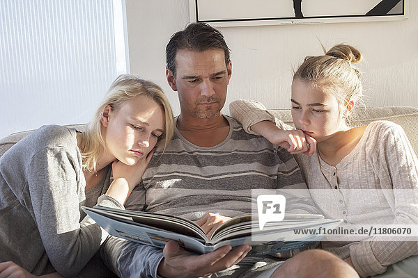 Teenage girls with father looking at book
