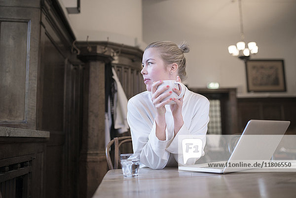 Woman drinking coffee in front of laptop