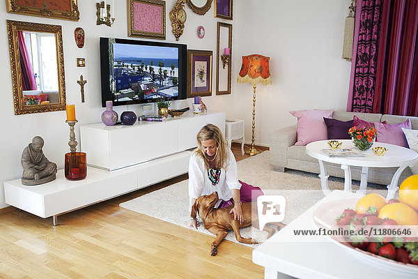 Frau spielt mit Hund im Wohnzimmer