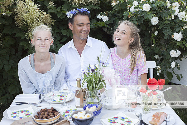 Vater mit Töchtern am Tisch im Garten