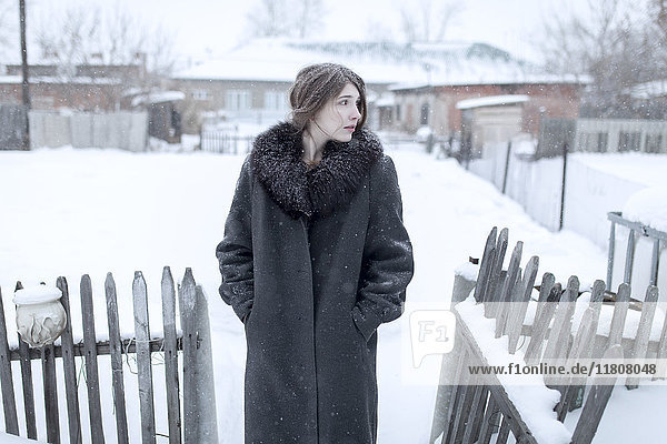 Caucasian woman wearing coat in winter near fence