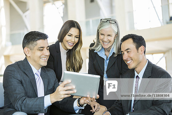 Lächelnde Geschäftsleute  die in der Lobby eine digitale Tafel lesen