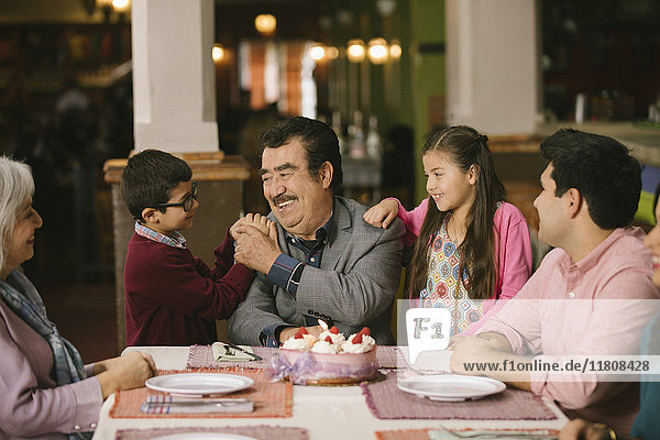 Family celebrating birthday or older man in restaurant