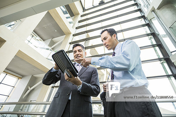 Businessmen using digital tablet in lobby