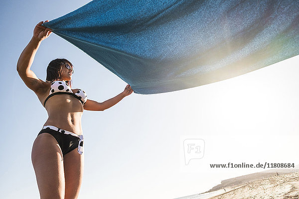 Kaukasische Frau breitet Decke am Strand aus