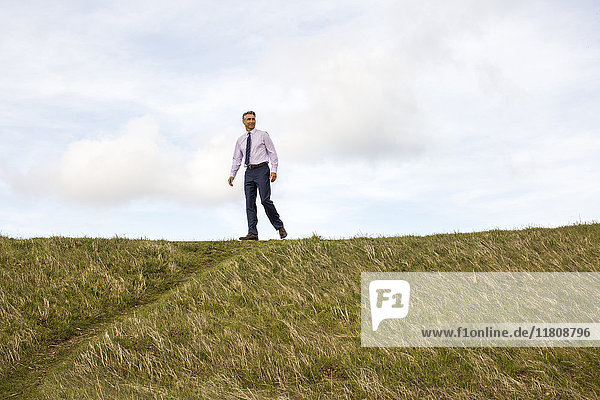 Caucasian businessman walking on hill
