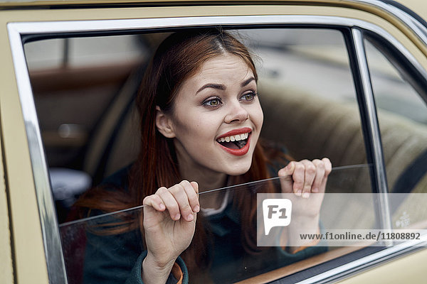 Kaukasische Frau lächelnd auf dem Rücksitz eines Autos