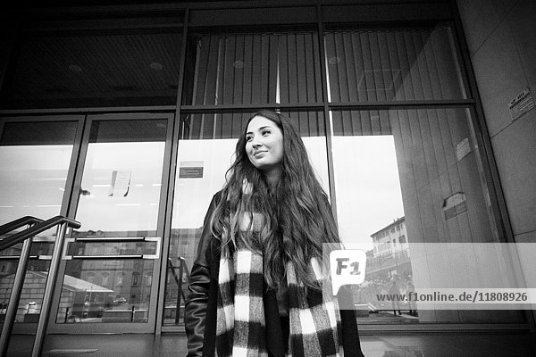 Lächelnde kaukasische Frau steht in der Nähe eines Gebäudes