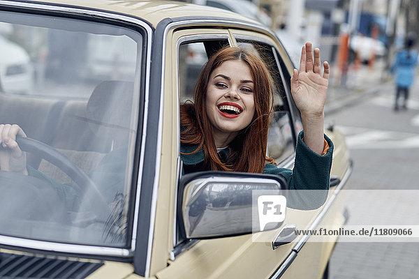 Smiling Caucasian woman driving car and waving