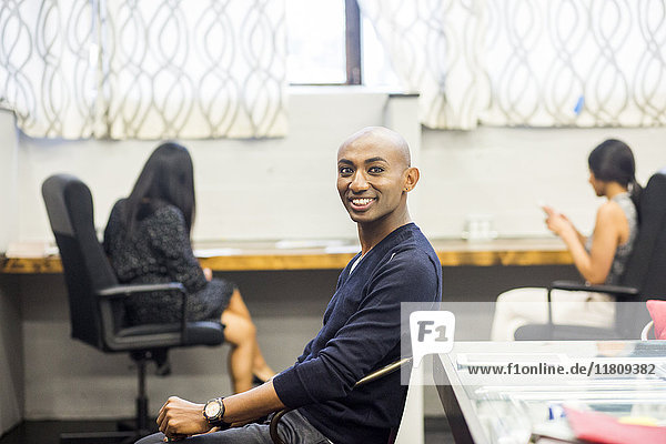 Porträt eines lächelnden afroamerikanischen Mannes  der in einem Büro sitzt