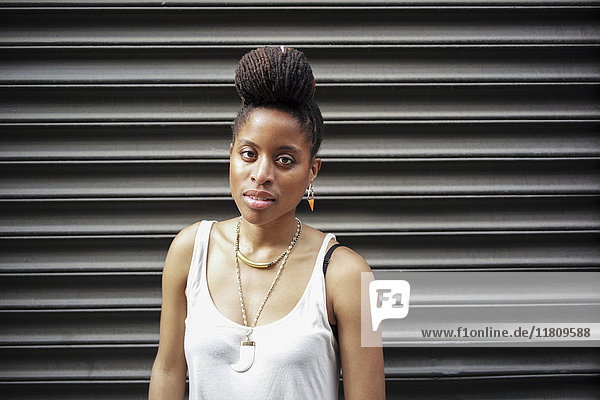 Porträt einer afroamerikanischen Frau mit Zöpfen in der Nähe einer Metallwand