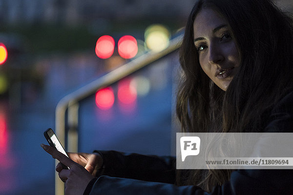 Porträt einer kaukasischen Frau  die im Freien eine SMS auf einem Mobiltelefon schreibt