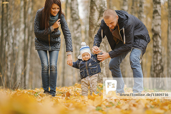 Eltern aus dem Nahen Osten gehen mit ihrem kleinen Sohn im Herbst spazieren