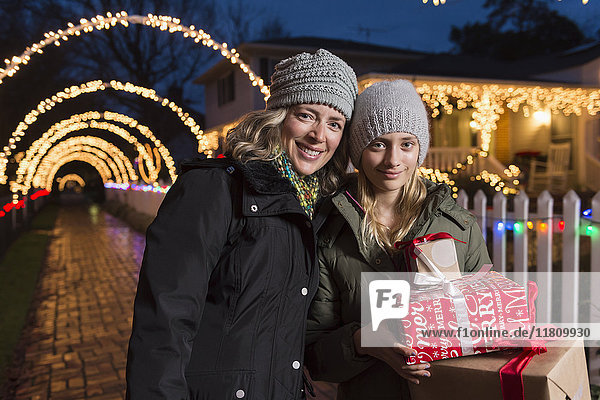 Kaukasische Mutter und Tochter halten Weihnachtsgeschenke auf dem Bürgersteig