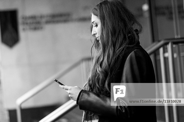 Seriöse kaukasische Frau  die eine SMS auf ihrem Handy schreibt