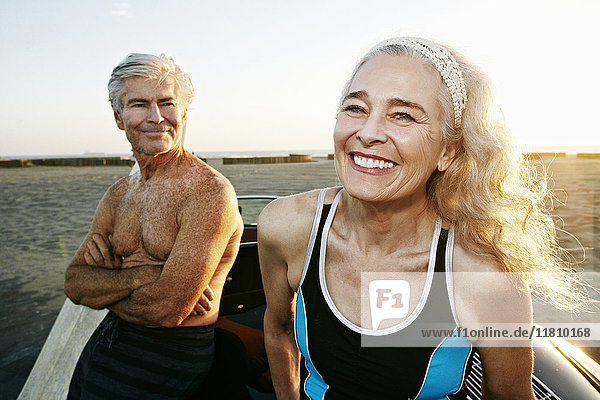 Älteres kaukasisches Paar lehnt an einem Cabrio am Strand