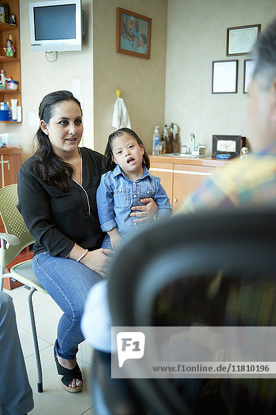 Hispanic mother and daughter with Down Syndrome talking to doctor