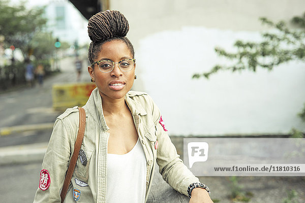 Seriöse afroamerikanische Frau mit Zöpfen und Brille
