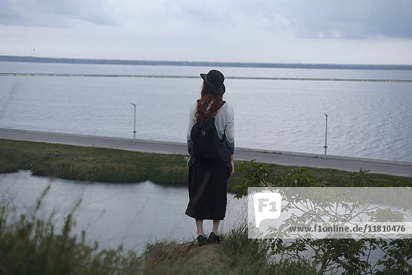 Kaukasische Frau steht auf einem Felsen und bewundert das Meer