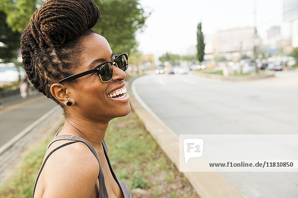 Afroamerikanische Frau mit Zöpfen lachend in der Nähe der Straße