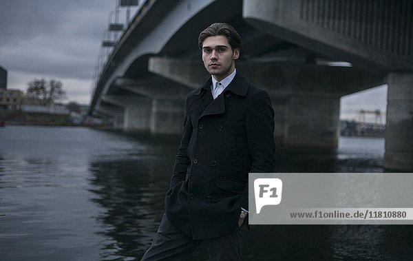 Porträt eines ernsten kaukasischen Mannes  der unter einer Brücke steht