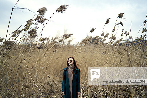 Caucasian woman standing in field with eyes closed