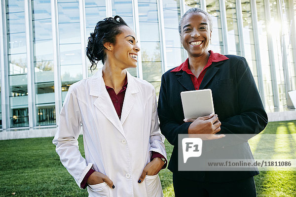 Doctor and administrator laughing outdoors at hospital