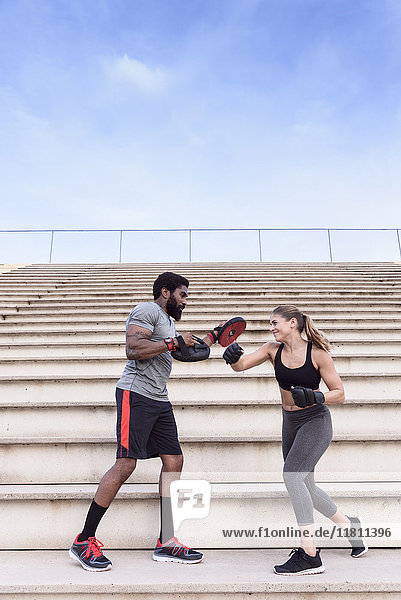 Trainer and woman boxing on bleachers