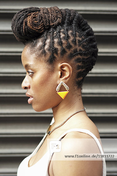 Profil einer afroamerikanischen Frau mit Zöpfen in der Nähe einer Metallwand