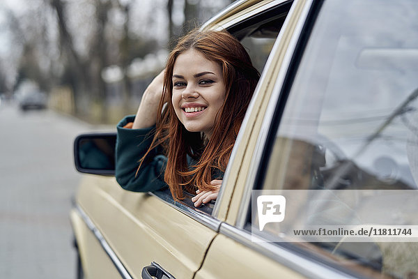 Lächelnde kaukasische Frau lehnt sich an die Autotür