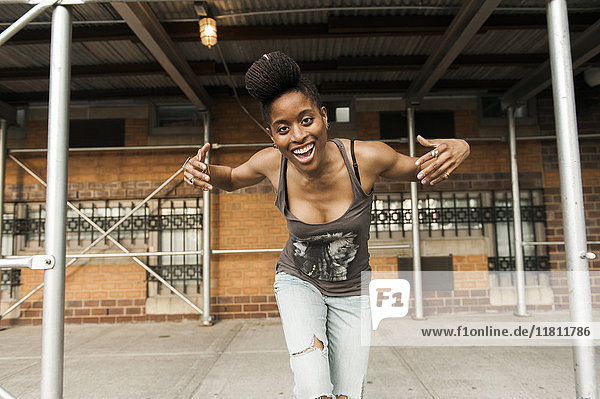 Lächelnde afroamerikanische Frau tanzt unter einem Baugerüst
