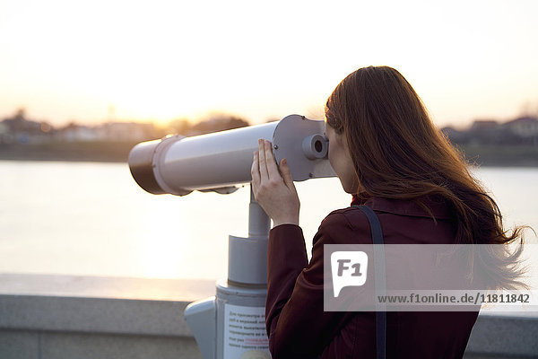 Caucasian woman using binoculars at waterfront