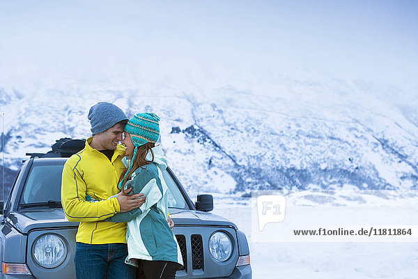 Caucasian couple hugging near car in winter