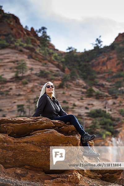 Caucasian woman sitting on edge of rock