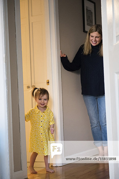 Mutter beobachtet kaukasische Baby-Tochter in der Tür stehend