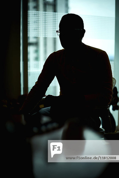 Silhouette of Hispanic man sitting at table