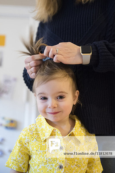 Kaukasische Mutter stylt das Haar ihrer kleinen Tochter