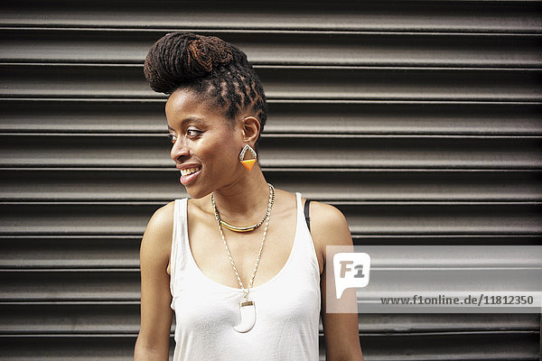 Porträt einer lächelnden afroamerikanischen Frau mit Zöpfen in der Nähe einer Metallwand