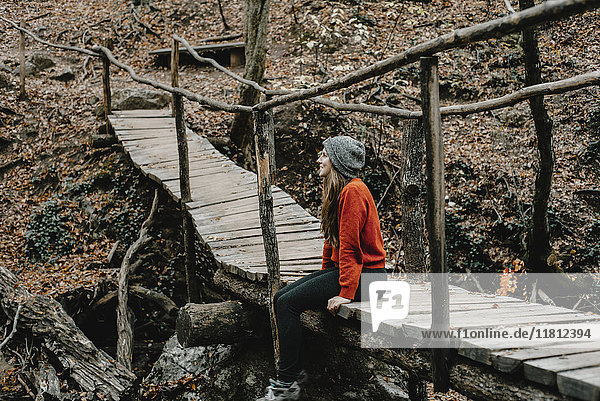 Kaukasische Frau sitzt auf einem Steg im Wald