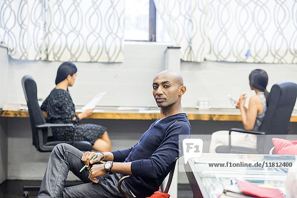 Porträt eines ernsten afroamerikanischen Mannes  der in einem Büro sitzt