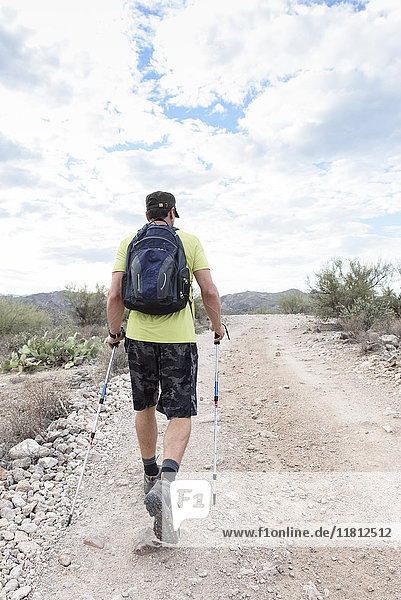 Hispanic man hiking on rocky path in desert