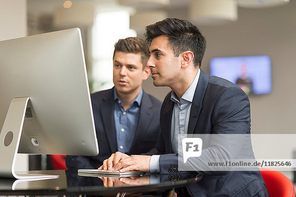 Two businessmen looking at office desktop computer