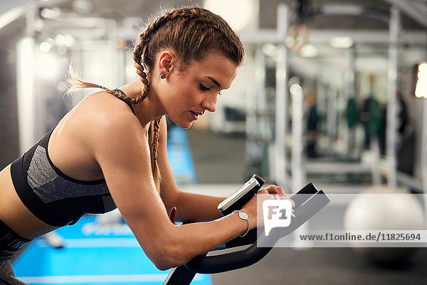 Young woman training  pedalling exercise bike in gym