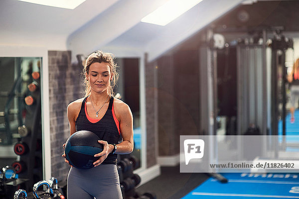 Junge Frau trainiert  hält Atlasball im Fitnessstudio