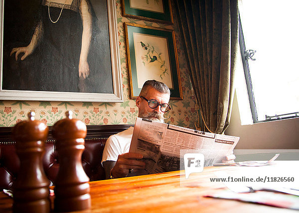 Schrulliger Mann liest Zeitungen in Bar und Restaurant  Bournemouth  England