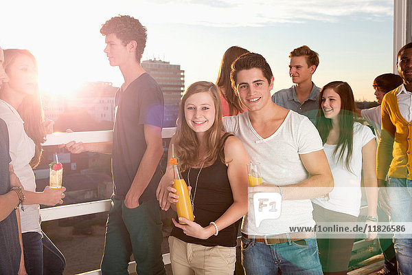 Couple at house party with friends on balcony