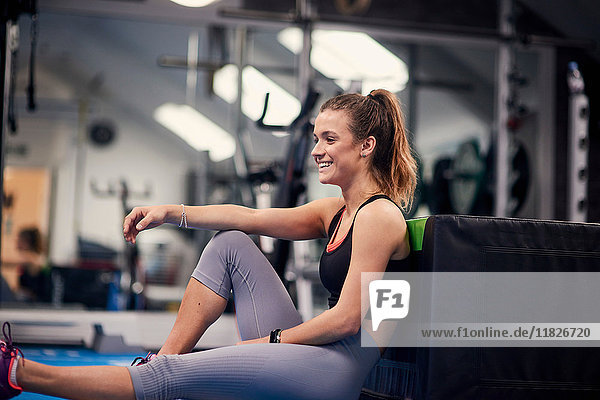 Happy young woman training  sitting on gym floor